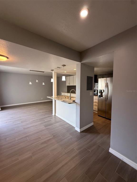 A kitchen with granite countertops and stainless steel appliances opens to a spacious living area — 6814 WHITMAN PLACE UNIT 6814, SARASOTA, FL