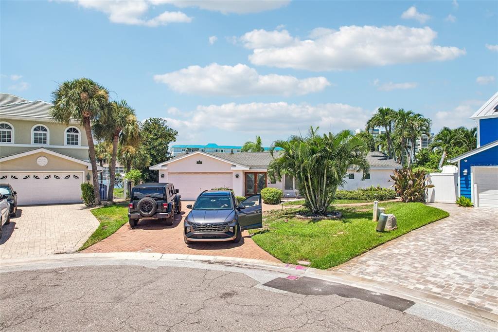 A single-story house with a brick driveway, two parked cars, and palm trees in front — 8078 13TH AVENUE S, ST PETERSBURG, FL
