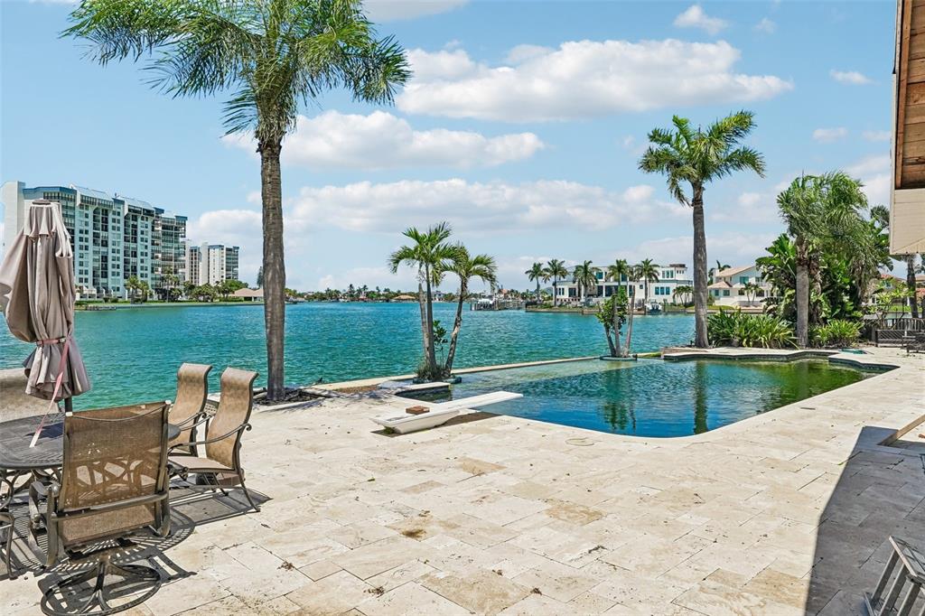 A patio with a pool and palm trees overlooks a bay with distant buildings — 8078 13TH AVENUE S, ST PETERSBURG, FL