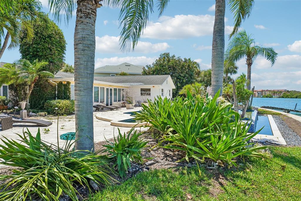 A white house with a pool and patio overlooks a canal surrounded by palm trees — 8078 13TH AVENUE S, ST PETERSBURG, FL