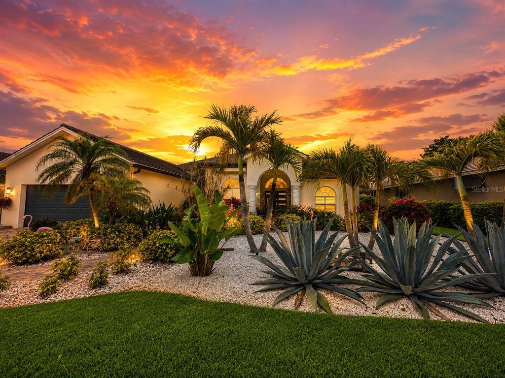A single-story house with palm trees and agave plants in the front yard at sunset — 810 OAK BRIAR LANE, OSPREY, FL