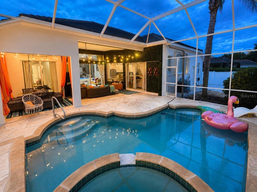 A swimming pool and hot tub sit inside a screened-in patio with outdoor seating — 810 OAK BRIAR LANE, OSPREY, FL