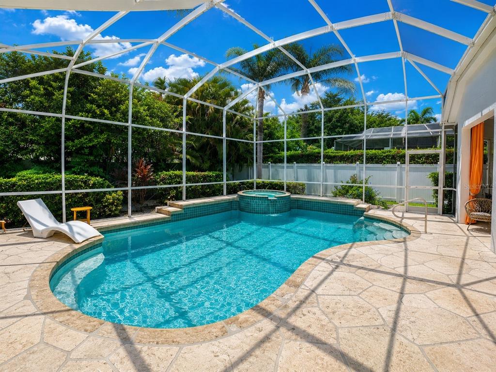 A screened-in swimming pool and spa with a stone patio and lush landscaping — 810 OAK BRIAR LANE, OSPREY, FL