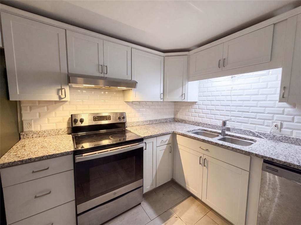 A kitchen with white cabinets, granite countertops, a stainless steel stove, and a subway tile backsplash — 3004 HUNKIN CIRCLE, DELTONA, FL