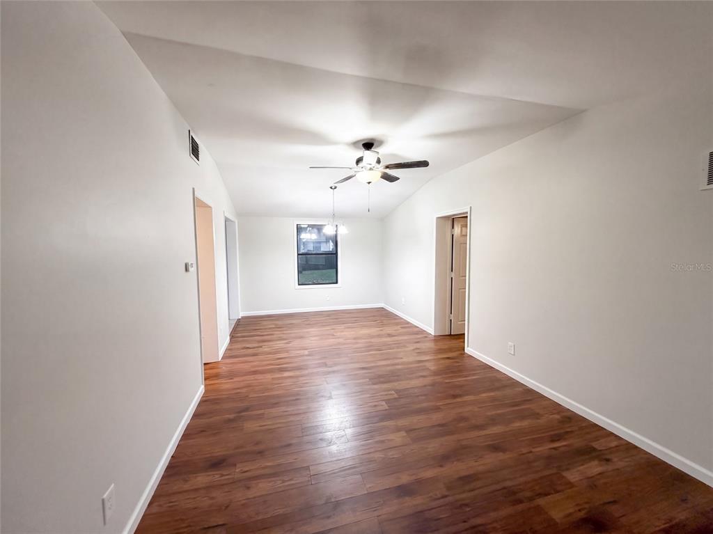 An empty room features wood-look flooring, white walls, a ceiling fan, and a single window — 3004 HUNKIN CIRCLE, DELTONA, FL