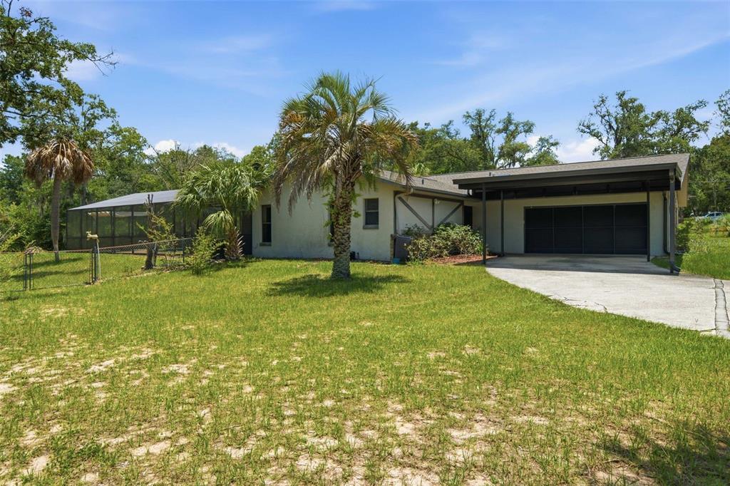 A single-story house with a screened-in porch, a carport, and a palm tree in front — 385 N CORNISH POINT, LECANTO, FL
