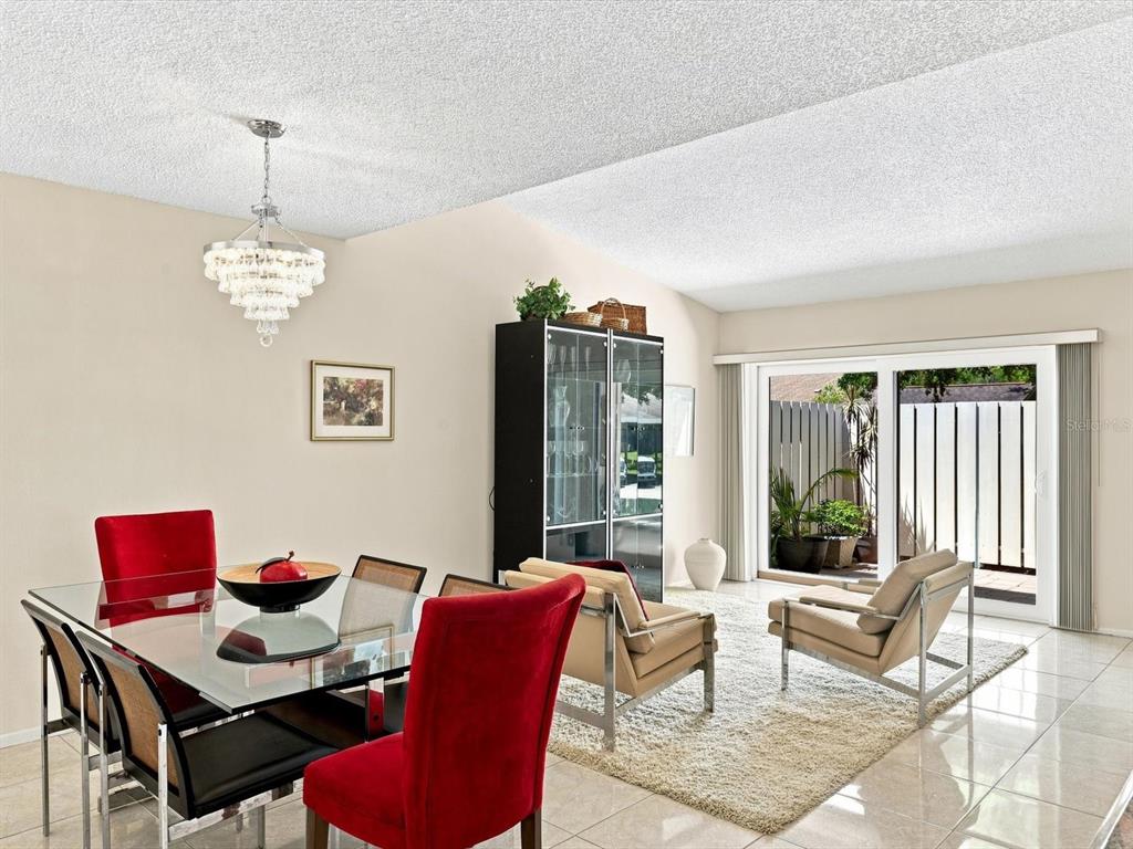 A dining area with a glass table and red chairs opens to a living space — 3450 TALLYWOOD LANE UNIT 7150, SARASOTA, FL