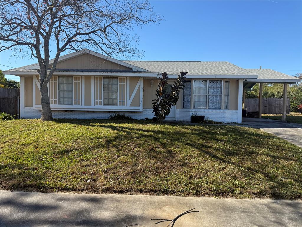 A single-story house with a tan exterior, white brick base, and an attached carport — 750 NE HAMPTON DRIVE, PALM BAY, FL