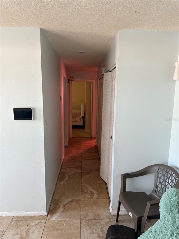 A hallway with tiled floors leads to a bedroom, featuring a wall-mounted smart home panel — 750 NE HAMPTON DRIVE, PALM BAY, FL