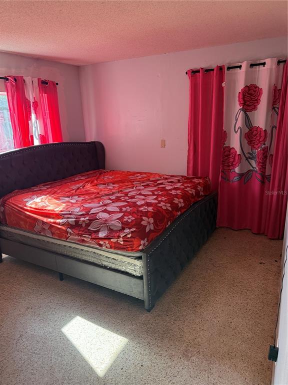 A bedroom features a dark tufted bed, floral bedding, and pink curtains over two windows — 750 NE HAMPTON DRIVE, PALM BAY, FL