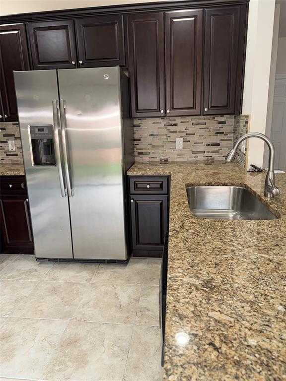 A kitchen features dark wood cabinets, granite countertops, stainless steel appliances, and a tiled backsplash — 1737 SOMMARIE WAY, TARPON SPRINGS, FL