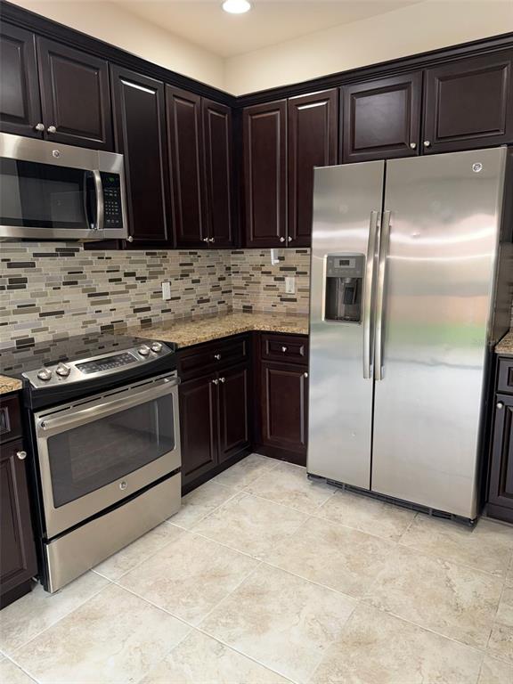 A kitchen features dark wood cabinets, granite countertops, stainless steel appliances, and a tiled floor — 1737 SOMMARIE WAY, TARPON SPRINGS, FL