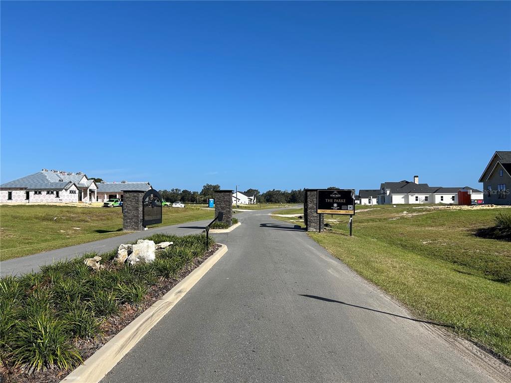 A paved road leads through a gated entrance into a neighborhood with new house construction — 5111 SW 125TH CIRCLE, ARCHER, FL