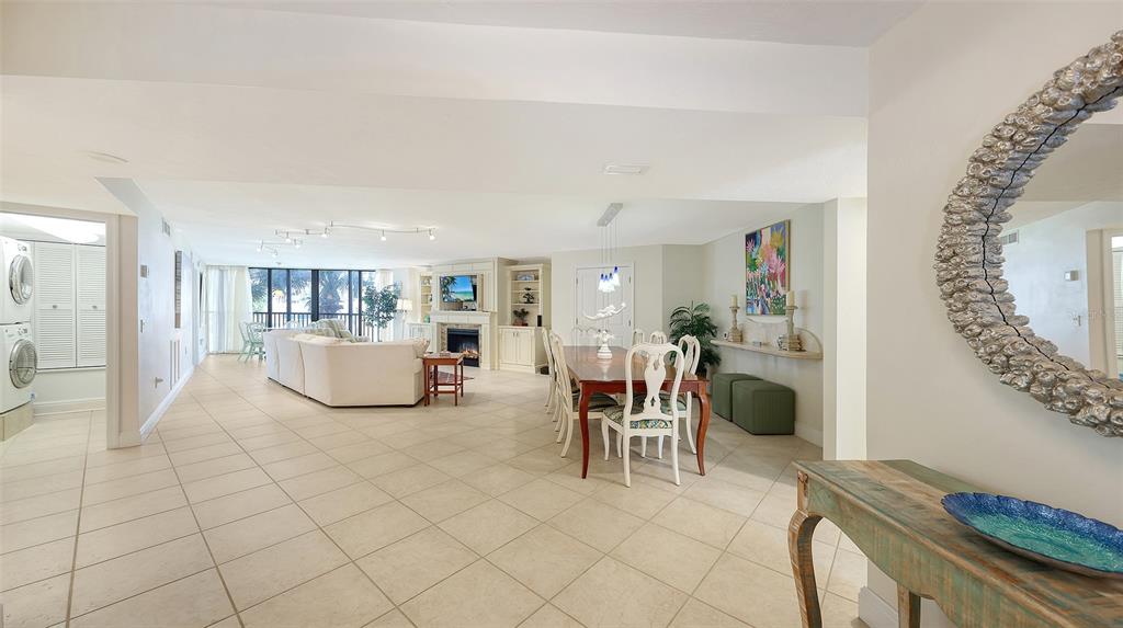 An open-concept living and dining area features tile flooring, a fireplace, and a large mirror — 5880 MIDNIGHT PASS ROAD UNIT 307, SARASOTA, FL