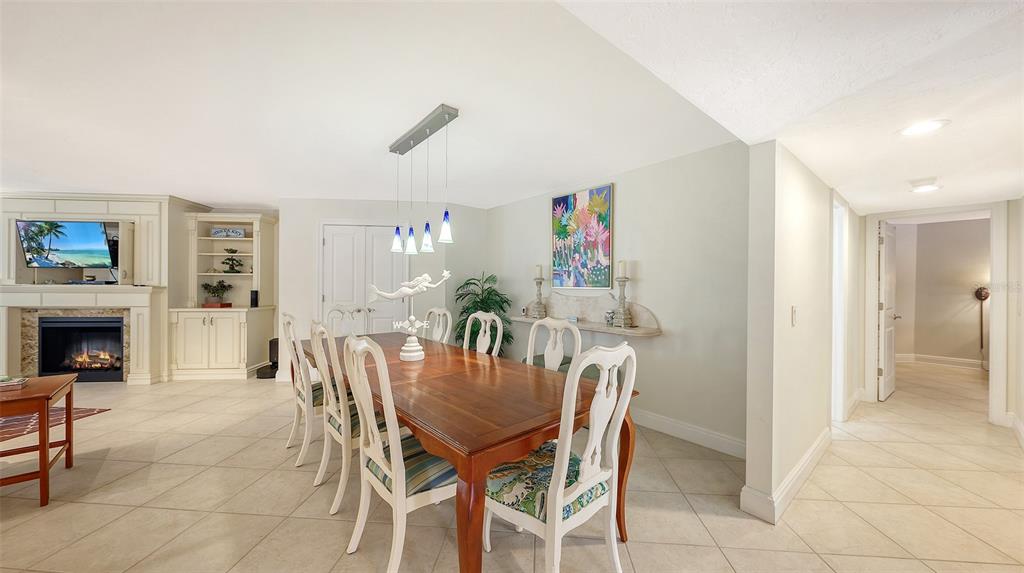 A dining room features a wooden table, white chairs, a fireplace, and tile flooring — 5880 MIDNIGHT PASS ROAD UNIT 307, SARASOTA, FL