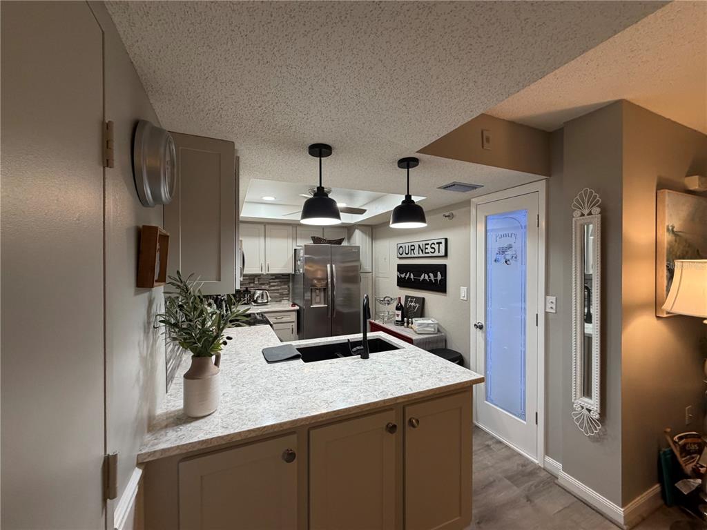A kitchen with a peninsula, light countertops, dark cabinets, and a pantry door — 21405 OLEAN BOULEVARD UNIT 521, PORT CHARLOTTE, FL