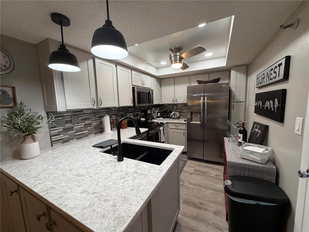 A kitchen features light gray cabinets, white quartz countertops, stainless steel appliances, and a black sink — 21405 OLEAN BOULEVARD UNIT 521, PORT CHARLOTTE, FL