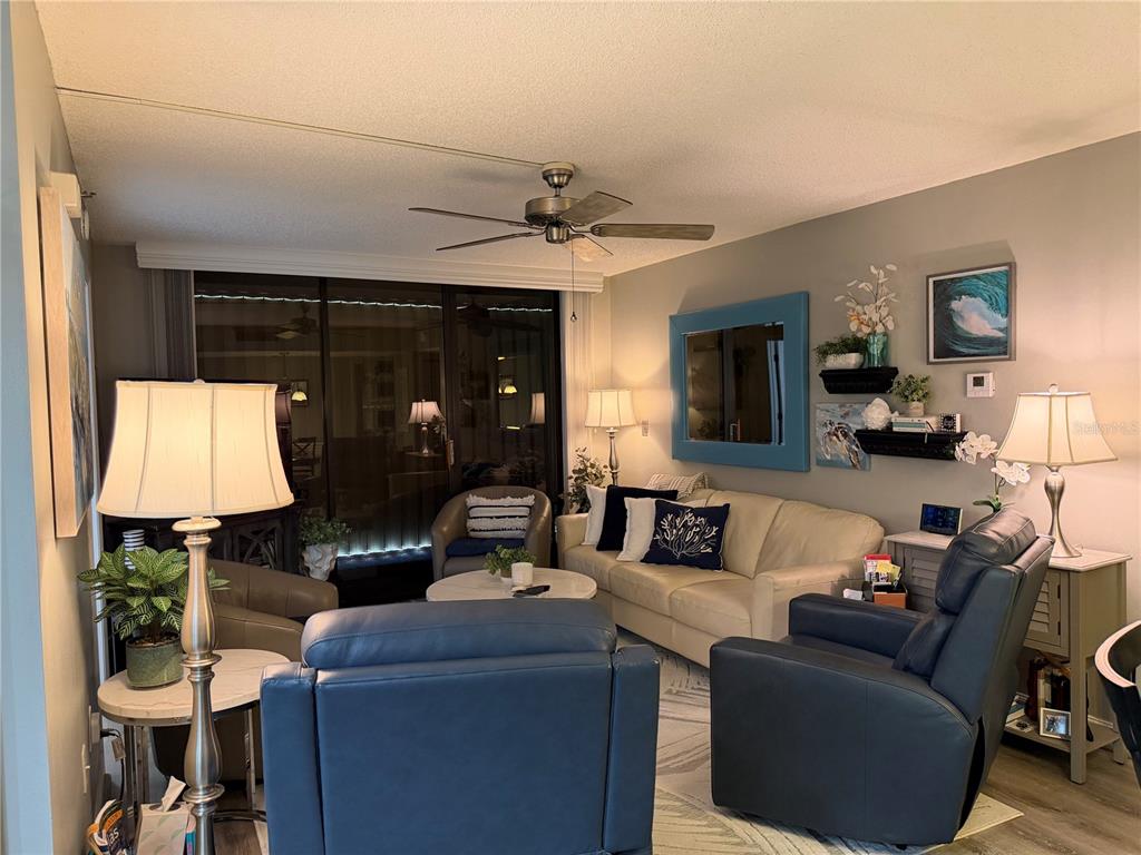A living room features a beige sofa, two blue armchairs, a ceiling fan, and sliding doors — 21405 OLEAN BOULEVARD UNIT 521, PORT CHARLOTTE, FL