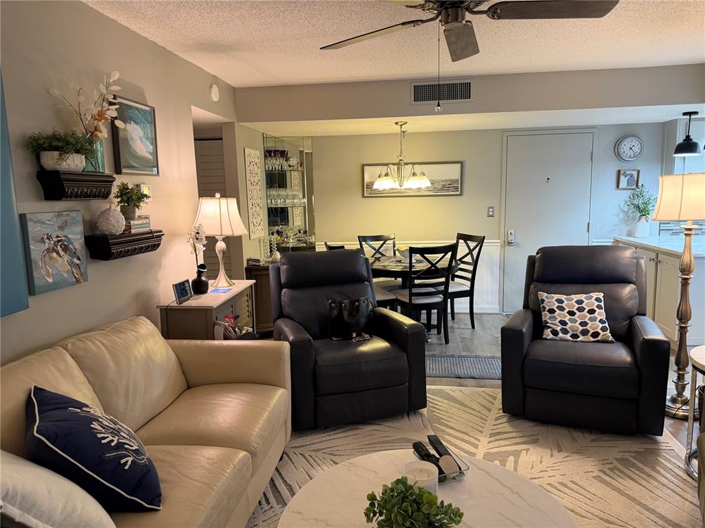 A living room with a beige sofa, two leather recliners, and an adjacent dining area — 21405 OLEAN BOULEVARD UNIT 521, PORT CHARLOTTE, FL
