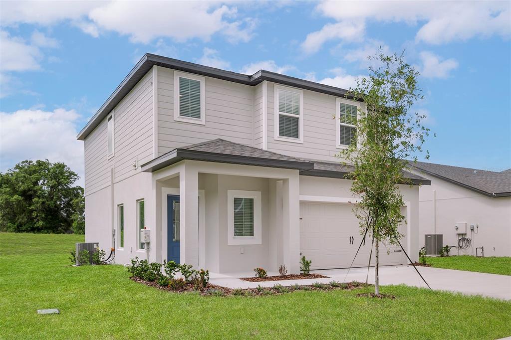 A two-story house with light gray siding, a white stucco front, and a blue door — 13280 TULA LOOP, ASTATULA, FL