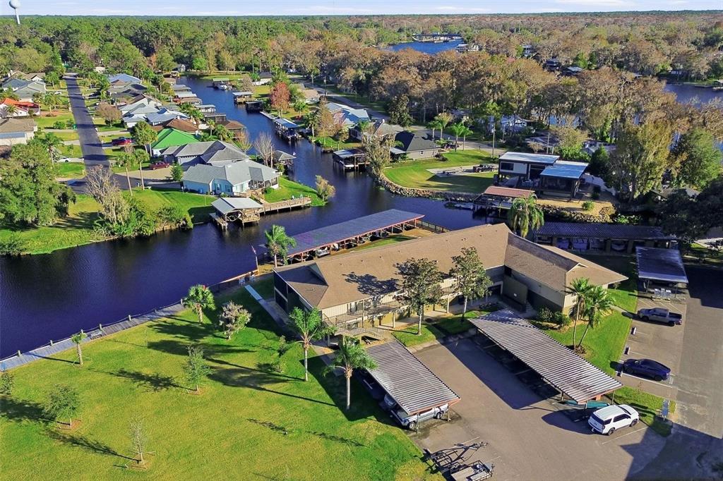 An aerial view shows a multi-unit building with carports next to a canal and homes — 1640 JUNO TRAIL UNIT 101H, ASTOR, FL