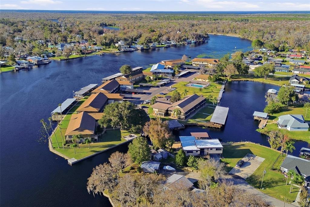 An aerial view of a waterfront apartment complex with boat docks and a swimming pool — 1640 JUNO TRAIL UNIT 101H, ASTOR, FL