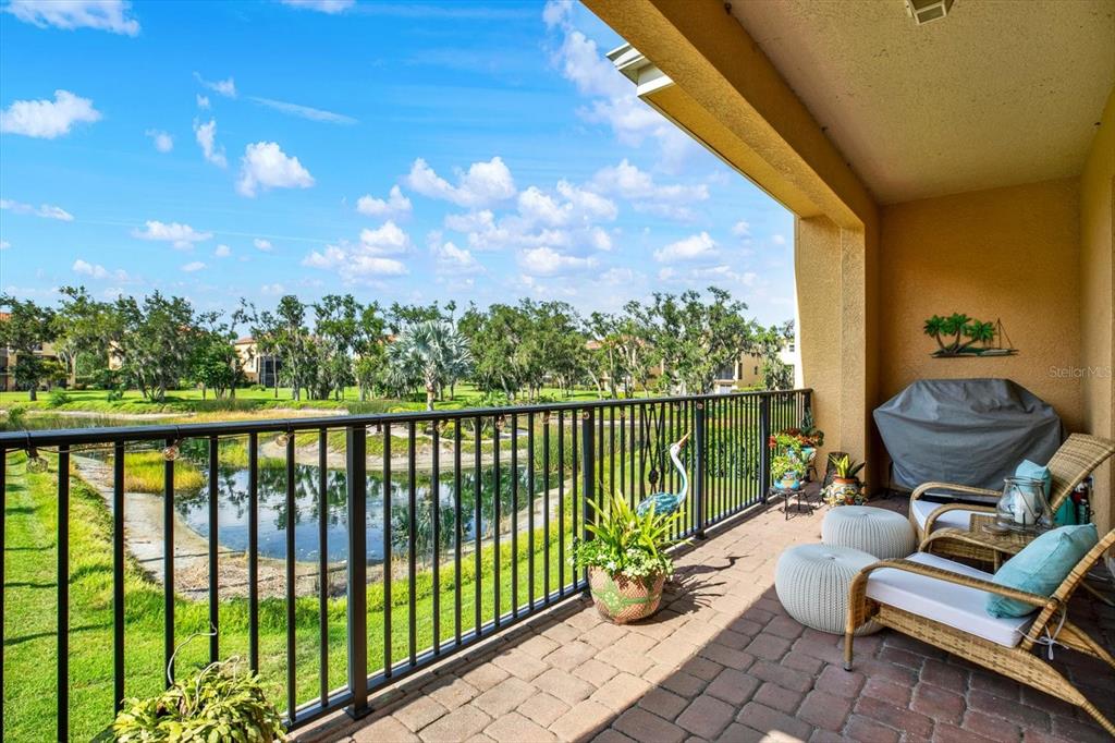 A covered patio with brick flooring, a metal railing, and a view of a pond — 1226 3RD STREET CIRCLE E, PALMETTO, FL
