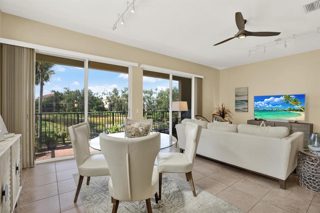 A living and dining area features tile floors, a glass table, and sliding glass doors — 1226 3RD STREET CIRCLE E, PALMETTO, FL