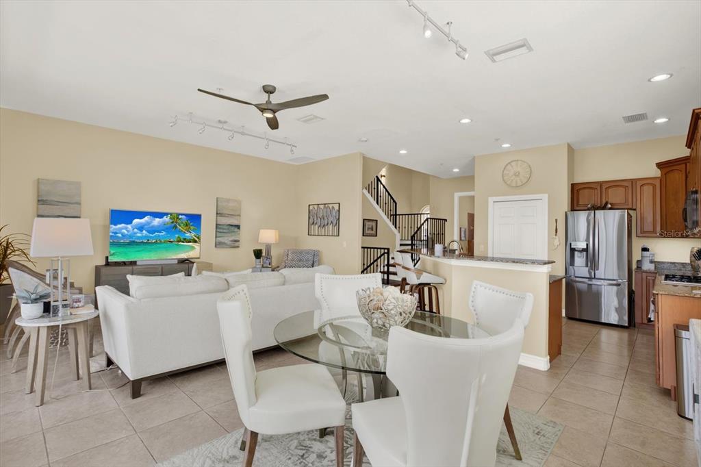 An open-concept living and dining area features tile flooring, a kitchen, and a staircase — 1226 3RD STREET CIRCLE E, PALMETTO, FL