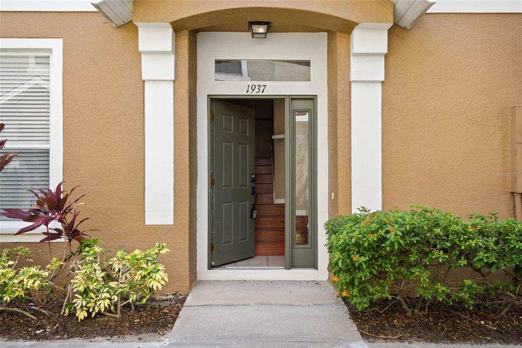 The exterior entrance features a tan stucco wall, a green door, and a small walkway — 1937 ESTANCIA CIRCLE UNIT 1937, KISSIMMEE, FL