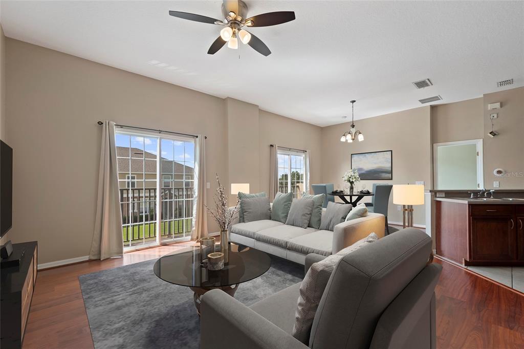 A living room with hardwood floors, a gray sofa, and a sliding glass door — 1937 ESTANCIA CIRCLE UNIT 1937, KISSIMMEE, FL