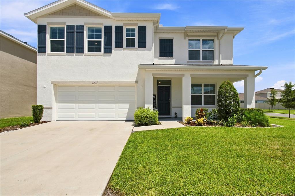 A two-story suburban house with a white stucco exterior, a garage, and a front porch — 33635 HAMILTON HILL LANE, WESLEY CHAPEL, FL