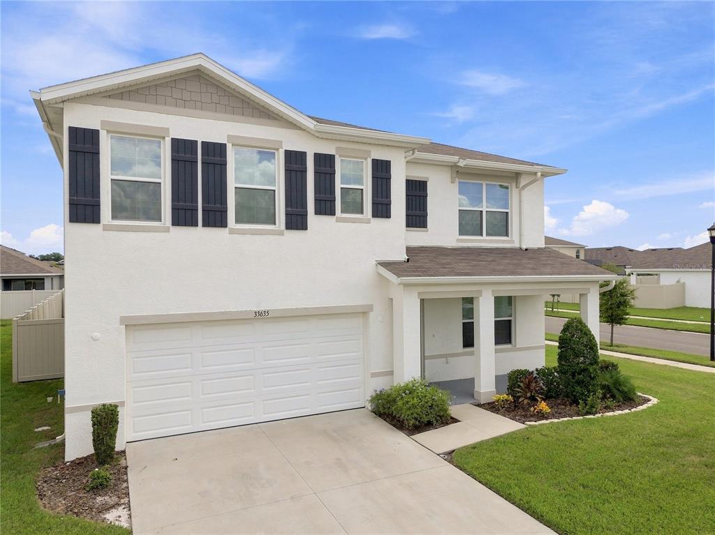 A two-story house with a white stucco exterior, a two-car garage, and a covered entryway — 33635 HAMILTON HILL LANE, WESLEY CHAPEL, FL