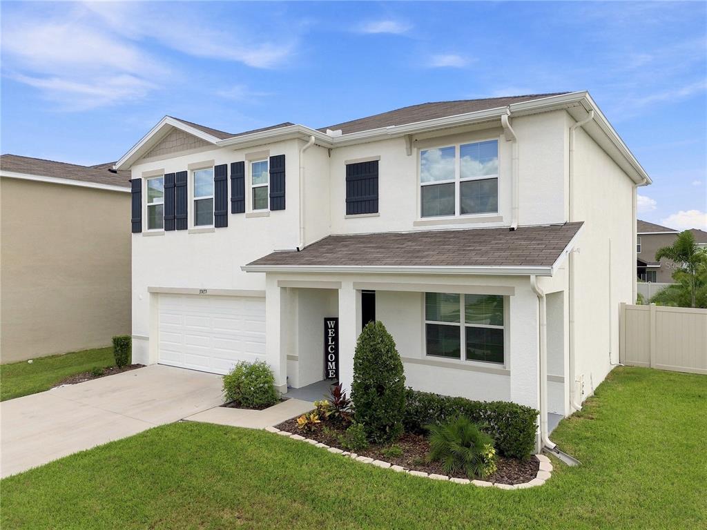 A two-story white house with a two-car garage, dark shutters, and a front porch — 33635 HAMILTON HILL LANE, WESLEY CHAPEL, FL