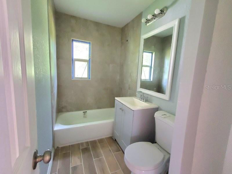 A bathroom features a white tub, a gray vanity, a toilet, and light-colored tiled flooring — 420 SOMERSET ROAD, PUNTA GORDA, FL