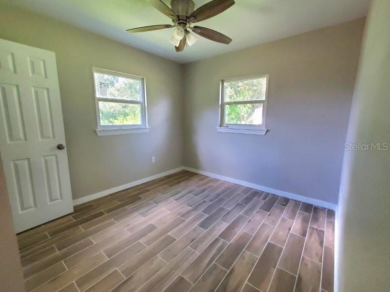 An empty bedroom features light-colored walls, a ceiling fan, and wood-look tile flooring — 420 SOMERSET ROAD, PUNTA GORDA, FL