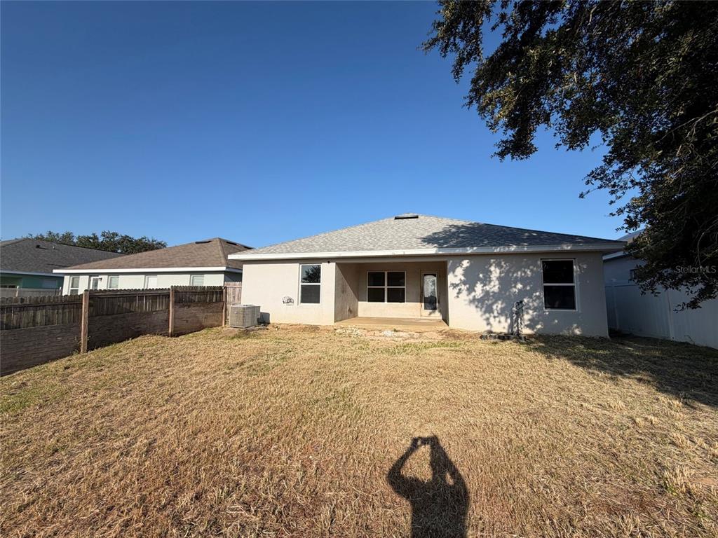 A view of the backyard and the rear exterior of a single-story house — 1229 LONGVILLE CIRCLE, TAVARES, FL