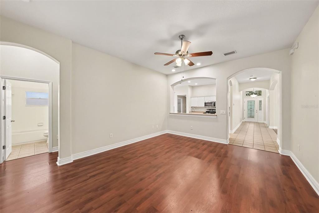 An empty room with hardwood floors, a ceiling fan, and arched doorways leading to other areas — 16312 BRIDGECROSSING DRIVE, LITHIA, FL