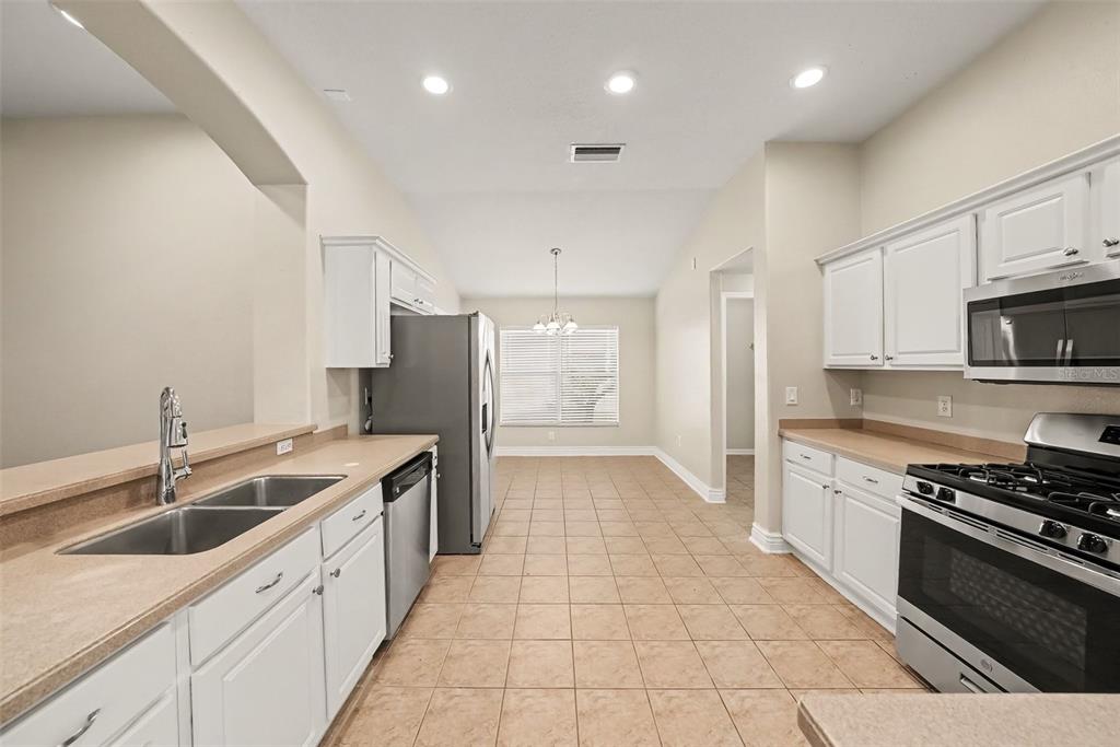 A kitchen with white cabinets, stainless steel appliances, and tan tile flooring — 16312 BRIDGECROSSING DRIVE, LITHIA, FL