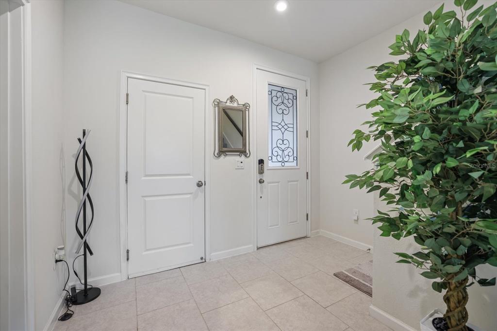 An entryway features white walls, tile flooring, a front door with glass, and a potted plant — 11814 SKY ACRES TERRACE, BRADENTON, FL