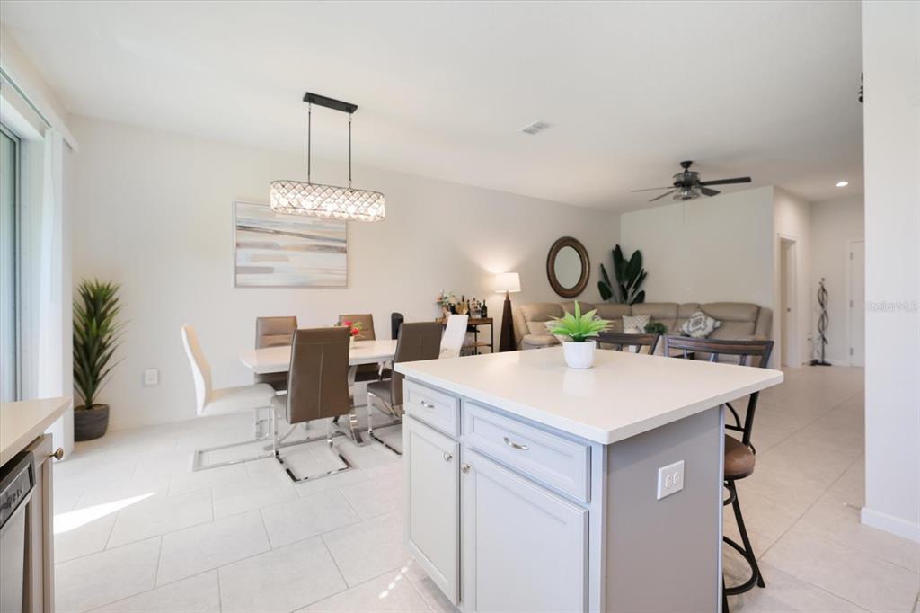 A kitchen island with a white countertop sits in front of an open-concept dining area — 11814 SKY ACRES TERRACE, BRADENTON, FL