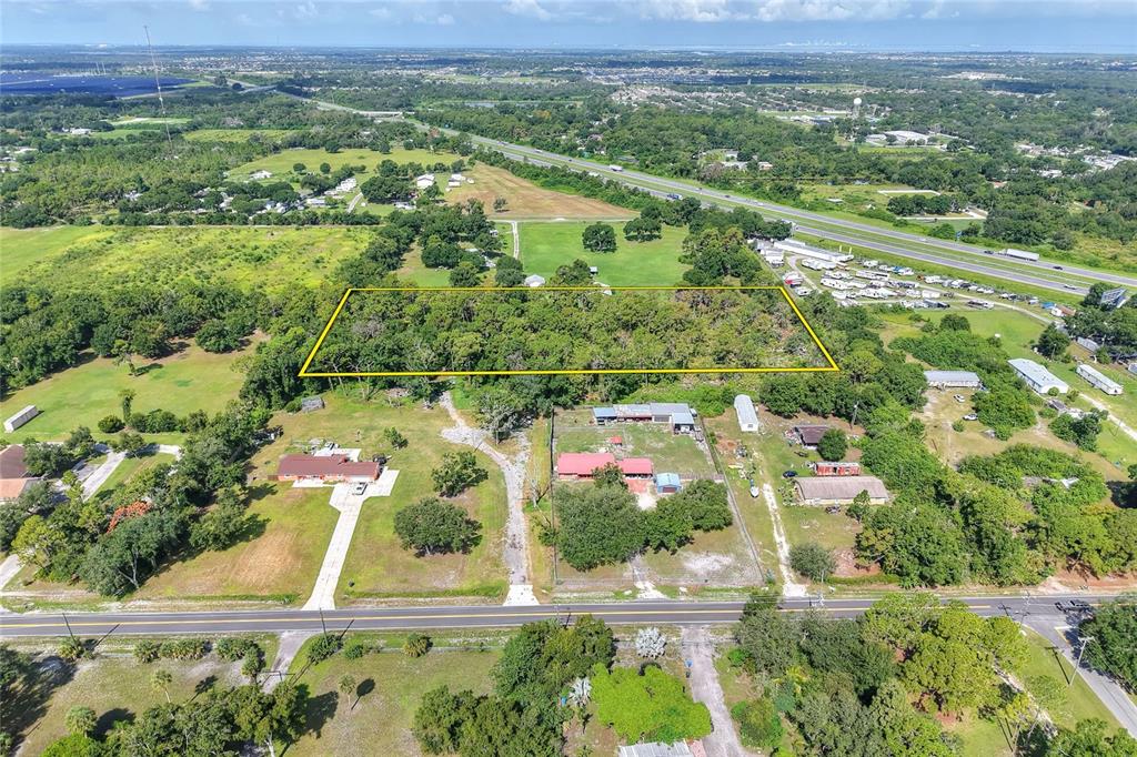 An aerial view shows a rectangular, wooded lot outlined in yellow with an access easement — SE 33RD STREET, RUSKIN, FL