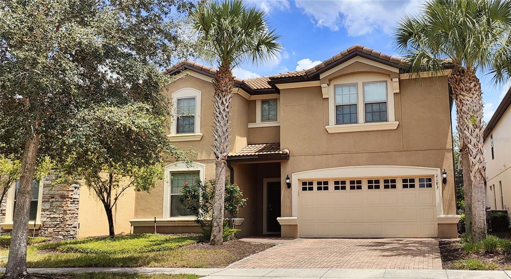 A two-story stucco house with a two-car garage and two palm trees in the front — 2183 TRIPOLI CT, KISSIMMEE, FL