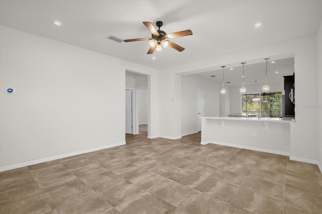 An open-concept living area features tile flooring, a ceiling fan, and a kitchen breakfast bar — 2444 VARENNA LOOP, KISSIMMEE, FL