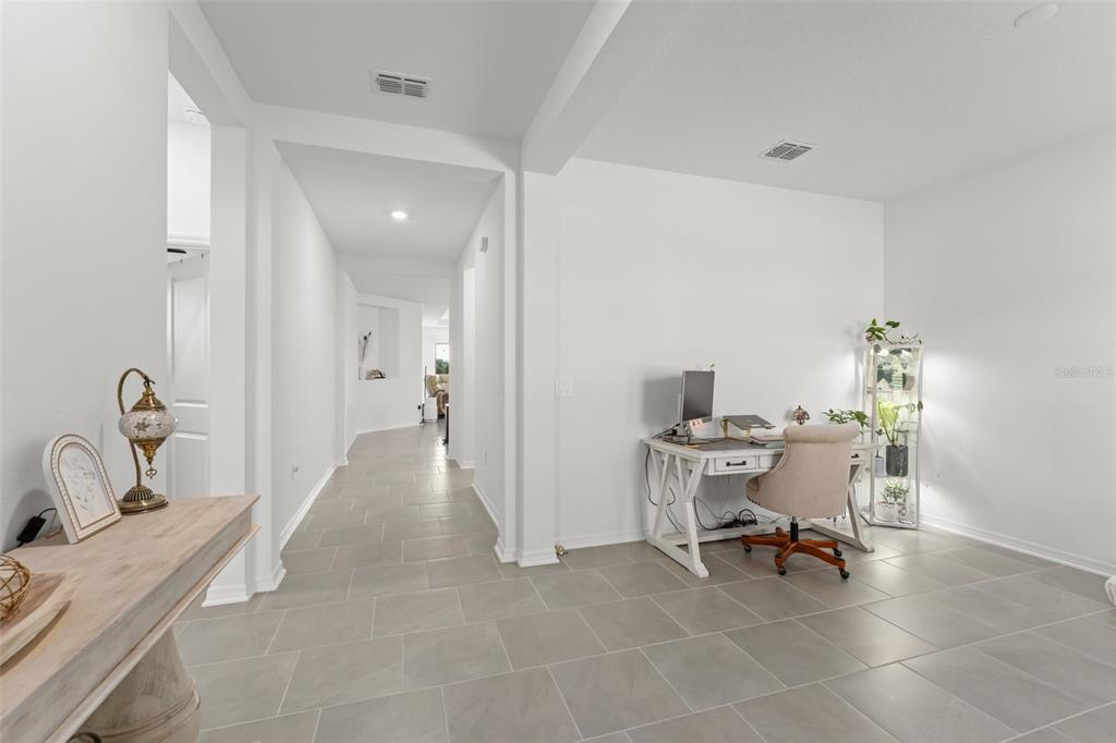 A bright home office area features a white desk, a chair, and tile flooring — 6025 CLAYSTONE WAY, MOUNT DORA, FL