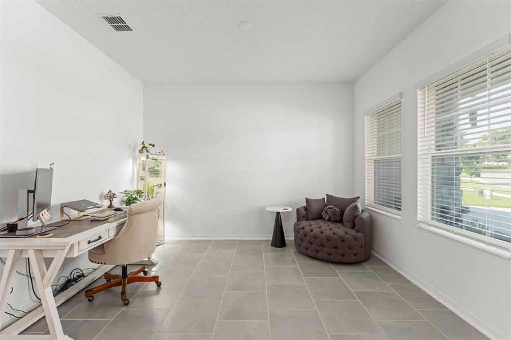 A home office with white walls, tile flooring, a desk, and a tufted round chair — 6025 CLAYSTONE WAY, MOUNT DORA, FL