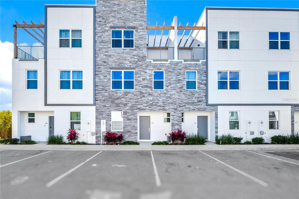 A modern three-story townhouse exterior features white panels, stone veneer, and a parking lot — 412 FAMAGUSTA, DAVENPORT, FL