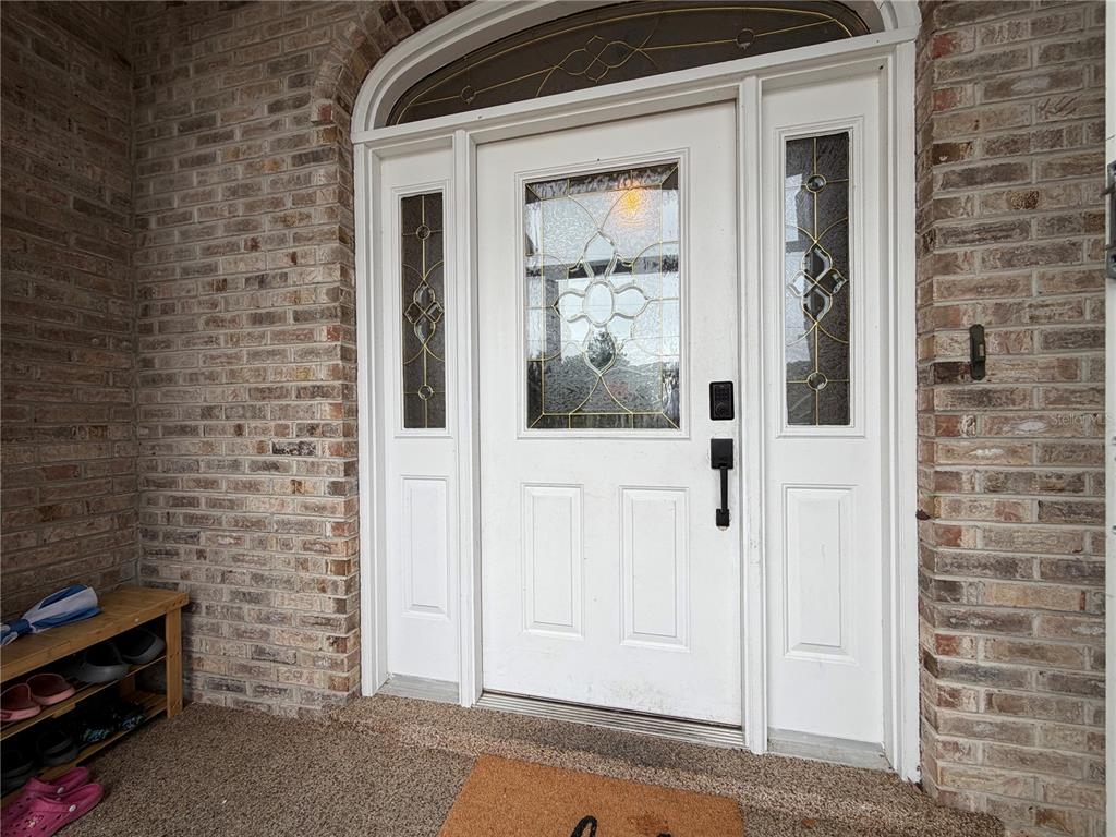 A white front door with glass panels and a transom window set in a brick wall — 51 FANSHAWE LANE, PALM COAST, FL