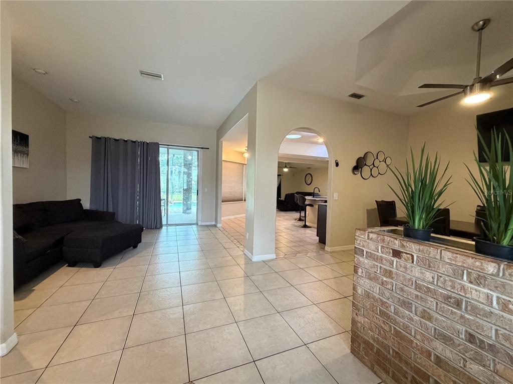 A living room with tile floors, a brick half-wall, and an arched doorway to the kitchen — 51 FANSHAWE LANE, PALM COAST, FL