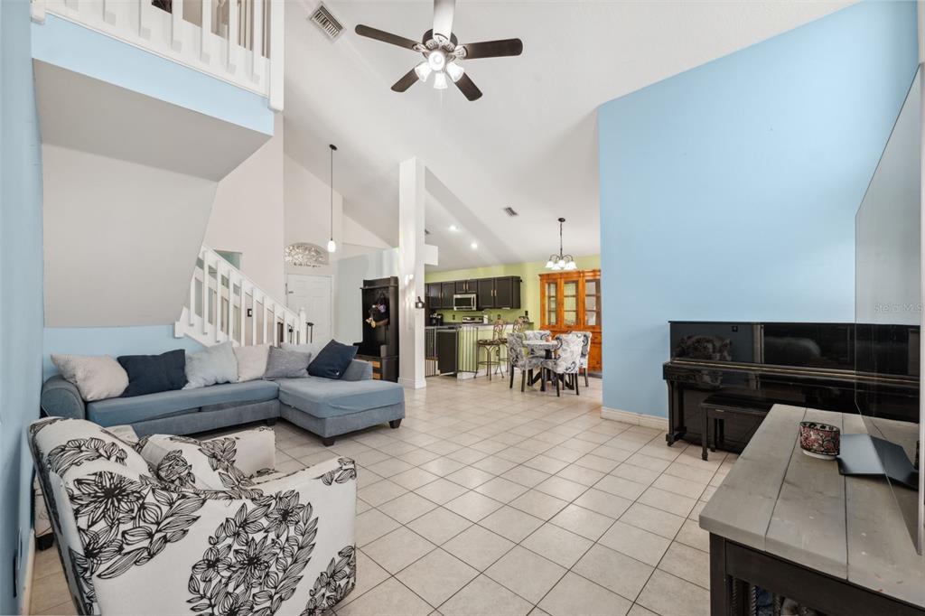 A living room with tile floors, a blue sectional sofa, and an open-concept kitchen area — 3316 PINE TOP DRIVE, VALRICO, FL